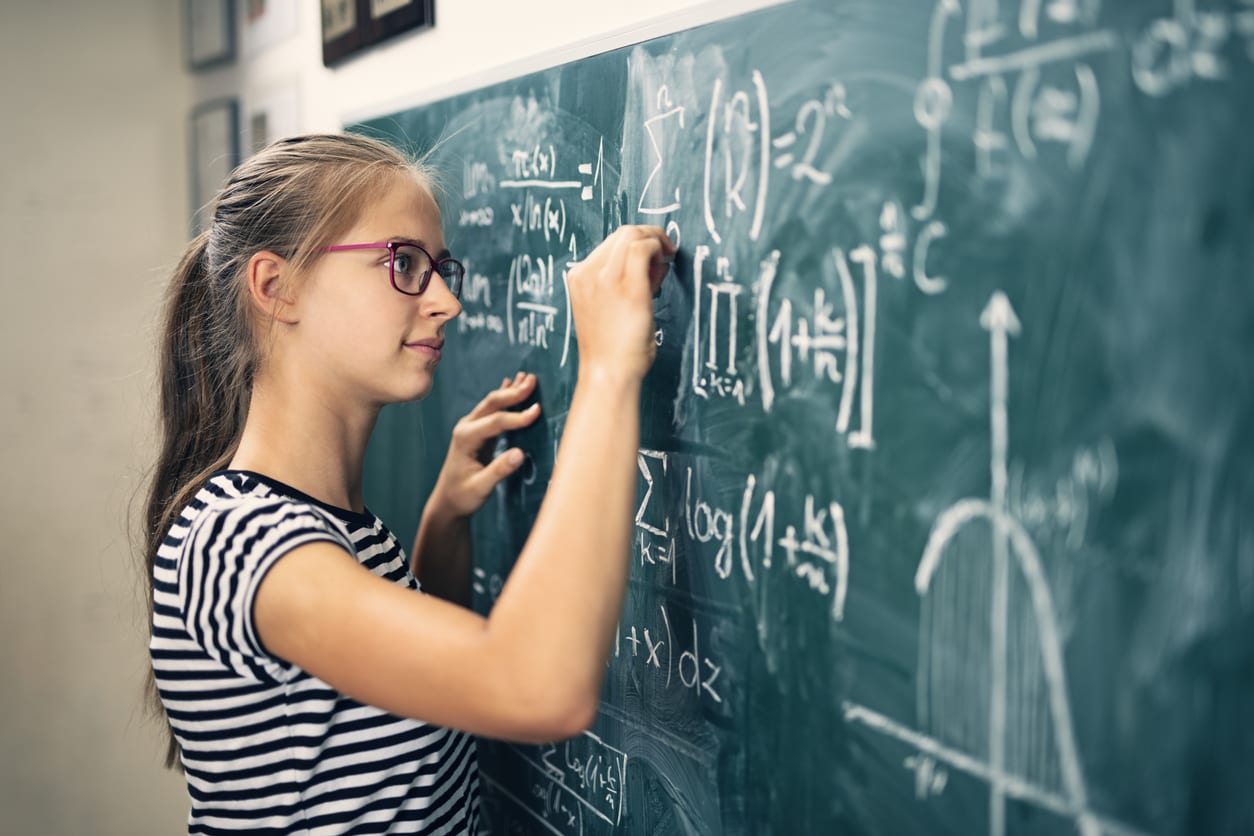 Teenager doing math on chalkboard at school